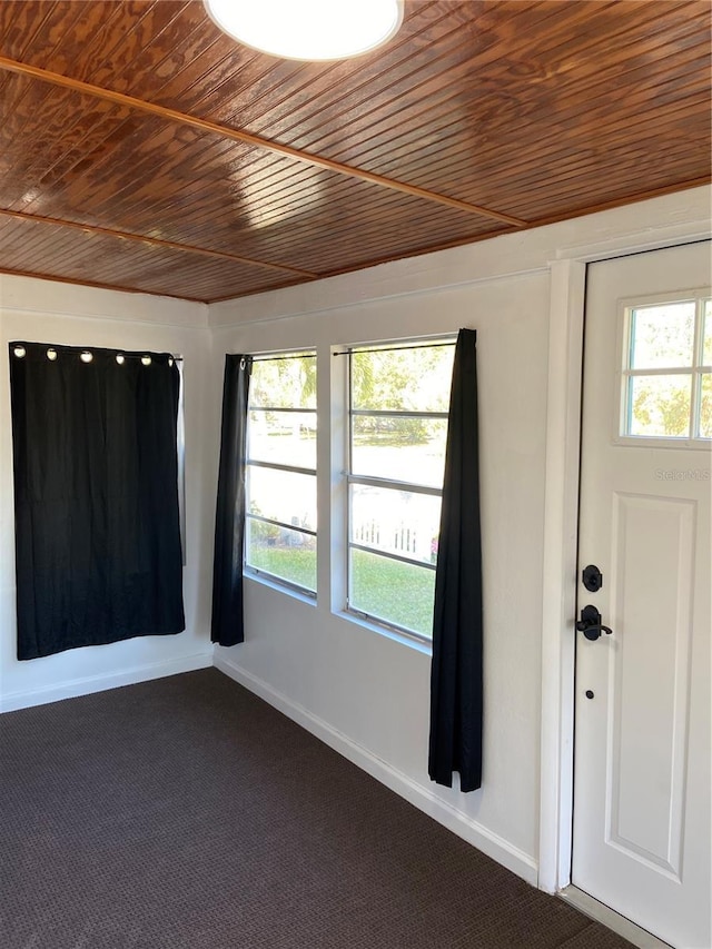 foyer with a healthy amount of sunlight, wood ceiling, and dark colored carpet