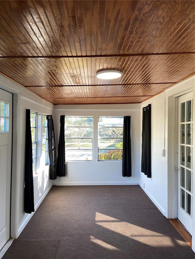 spare room featuring dark colored carpet, plenty of natural light, and wood ceiling