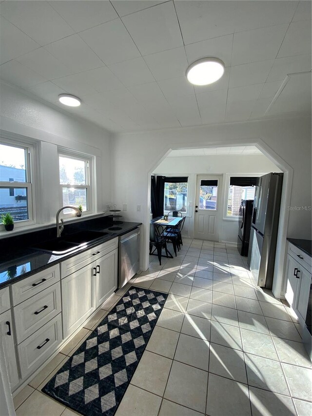 222 27th St W, Bradenton, FL 34205 - kitchen featuring dishwasher, dark countertops, light tile patterned flooring, and white cabinetry