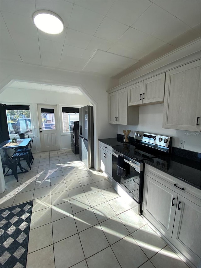 kitchen with washer and clothes dryer, light tile patterned flooring, and stainless steel appliances