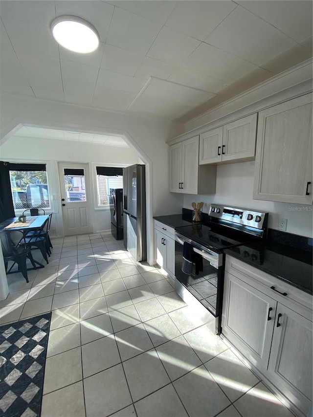 222 27th St W, Bradenton, FL 34205 - kitchen featuring stainless steel electric range, dark countertops, washer and clothes dryer, and light tile patterned floors