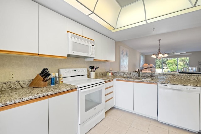 kitchen with white appliances, white cabinets, ceiling fan with notable chandelier, sink, and light stone counters