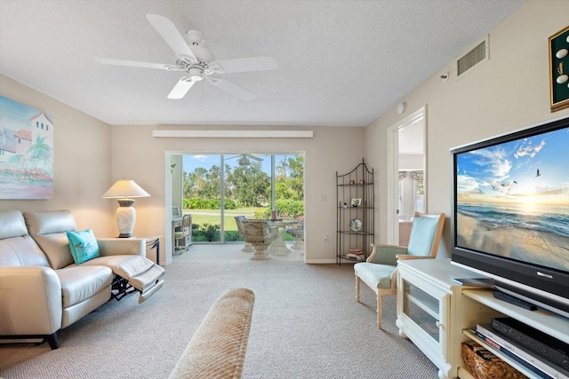 carpeted living room featuring ceiling fan and a textured ceiling