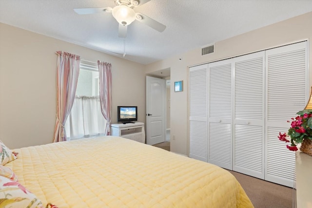 carpeted bedroom with a textured ceiling, a closet, and ceiling fan