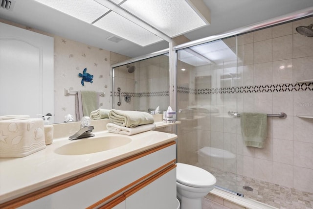 bathroom featuring tile patterned flooring, vanity, toilet, and walk in shower