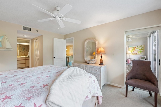 bedroom featuring light carpet, ensuite bathroom, ceiling fan, a textured ceiling, and a closet