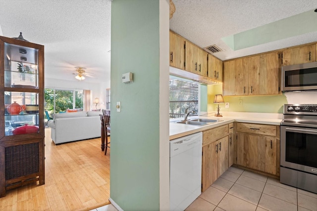 kitchen featuring sink, light hardwood / wood-style flooring, ceiling fan, a textured ceiling, and appliances with stainless steel finishes