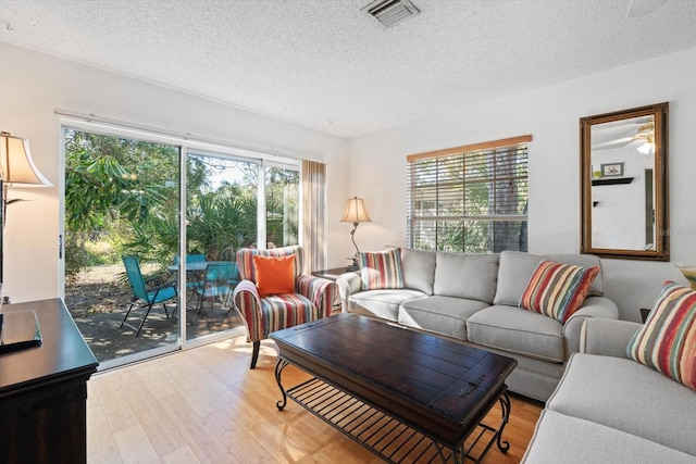 living room featuring ceiling fan, hardwood / wood-style floors, and a textured ceiling