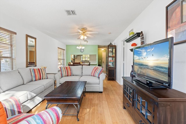 living room featuring ceiling fan with notable chandelier and light wood-type flooring