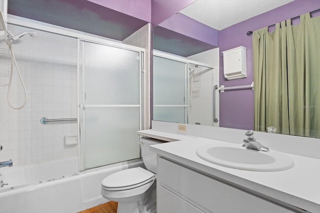 full bathroom featuring vanity, shower / bath combination with glass door, hardwood / wood-style flooring, toilet, and a textured ceiling