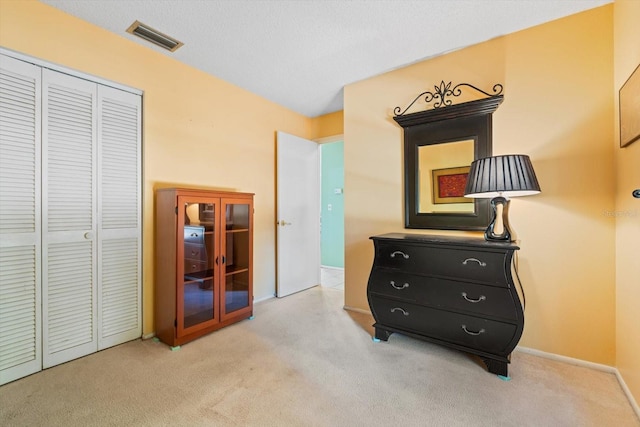 bedroom with light carpet, a closet, and a textured ceiling