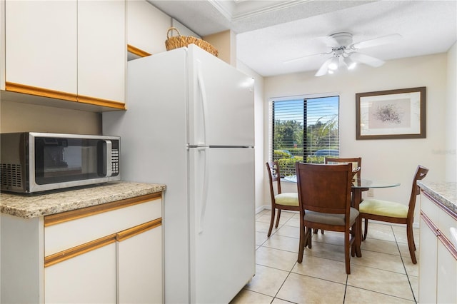 kitchen featuring white cabinets, white refrigerator, ceiling fan, a textured ceiling, and light tile patterned flooring