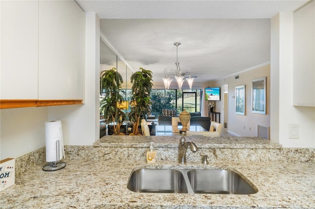 kitchen featuring white cabinetry, sink, a chandelier, and ornamental molding