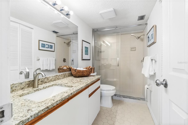 bathroom with vanity, a shower with door, tile patterned flooring, toilet, and a textured ceiling