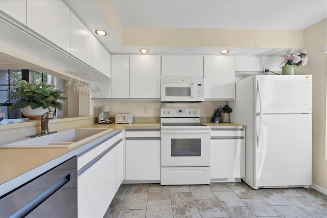 kitchen with white appliances, white cabinetry, and sink