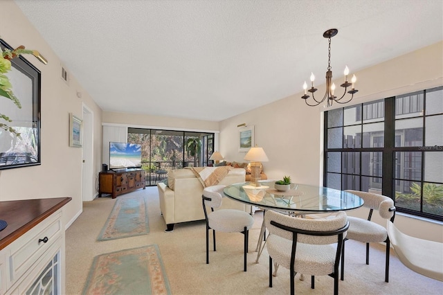 dining room with a chandelier, a textured ceiling, and light colored carpet