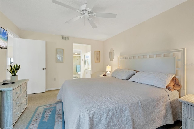 bedroom with connected bathroom, light colored carpet, and ceiling fan