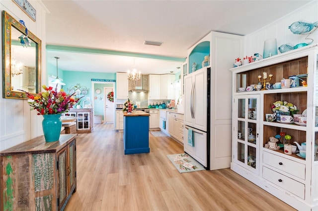 kitchen with wooden counters, white refrigerator, a center island, light hardwood / wood-style floors, and hanging light fixtures