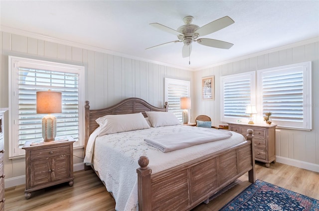 bedroom featuring multiple windows, ceiling fan, wood-type flooring, and ornamental molding