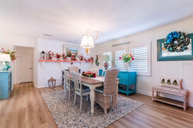 dining room with light wood-type flooring and brick wall