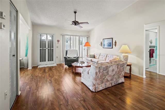 living room with ceiling fan, dark hardwood / wood-style flooring, and a textured ceiling