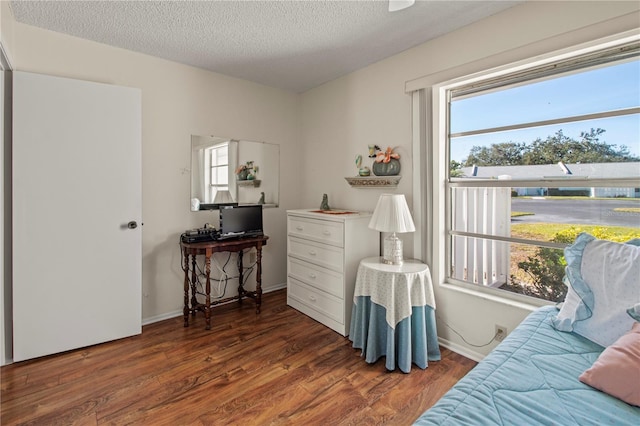 bedroom featuring multiple windows, dark hardwood / wood-style flooring, and a textured ceiling