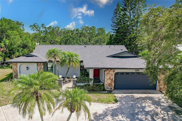 7707 10th Ave NW, Bradenton, FL 34209 - view of front of property with stone siding, concrete driveway, an attached garage, and roof with shingles