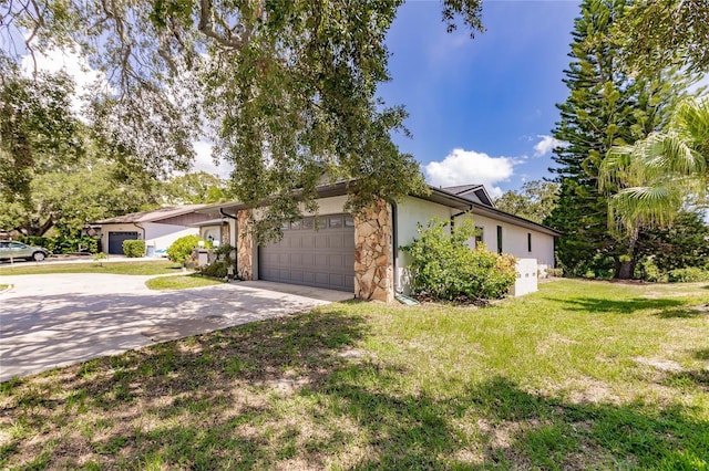 7707 10th Ave NW, Bradenton, FL 34209 - view of side of home with stone siding, an attached garage, driveway, a lawn, and stucco siding