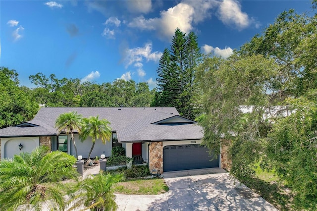 7707 10th Ave NW, Bradenton, FL 34209 - view of front of house with stone siding, an attached garage, driveway, and roof with shingles