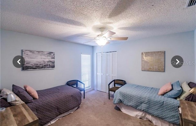 carpeted bedroom with ceiling fan, a closet, and a textured ceiling