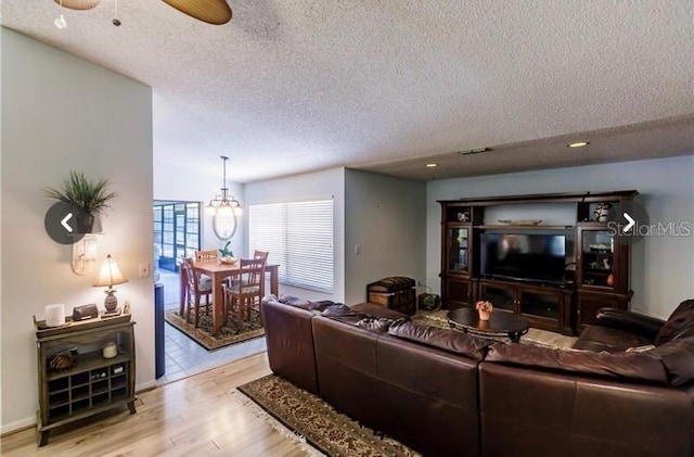 living room with a textured ceiling, light hardwood / wood-style floors, and ceiling fan