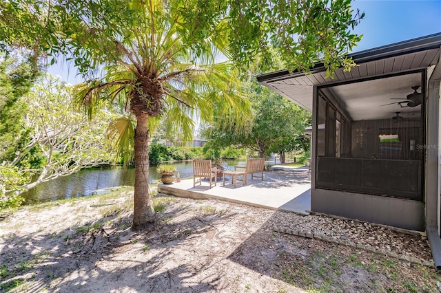 view of yard featuring a patio, a water view, ceiling fan, and a sunroom