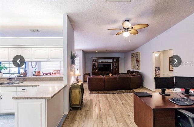 kitchen with a textured ceiling, ceiling fan, sink, white cabinets, and light hardwood / wood-style floors