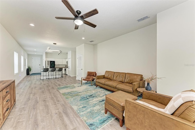 living room featuring a textured ceiling, light wood-type flooring, and ceiling fan