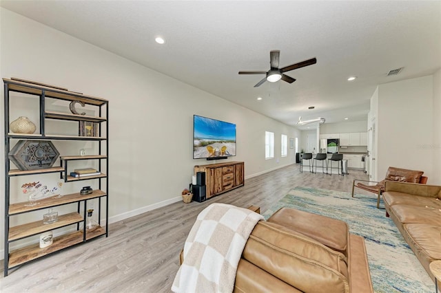 living room featuring ceiling fan, light hardwood / wood-style floors, and a textured ceiling