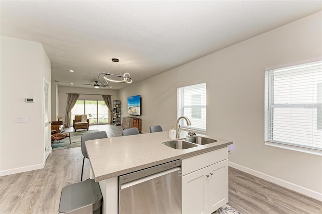 kitchen featuring white cabinetry, dishwasher, sink, light hardwood / wood-style flooring, and pendant lighting