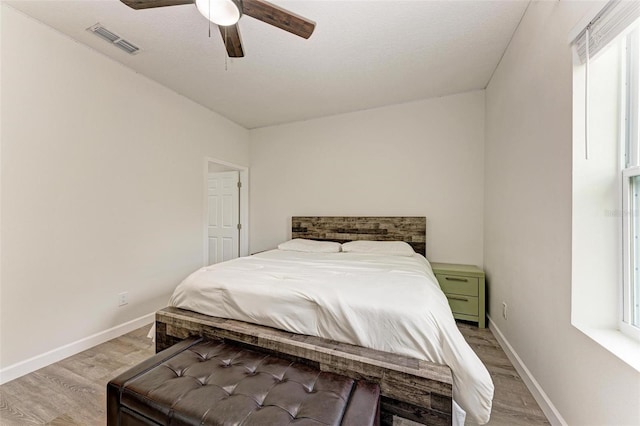 bedroom featuring ceiling fan, light wood-type flooring, and a textured ceiling