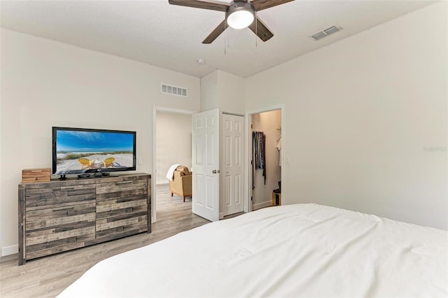 bedroom with a textured ceiling, light hardwood / wood-style floors, and ceiling fan