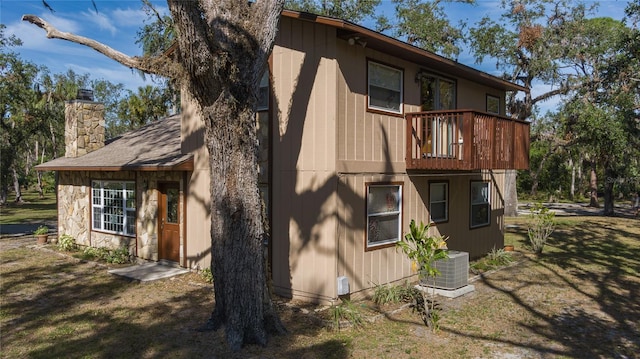 back of house with a lawn, central AC, and a balcony