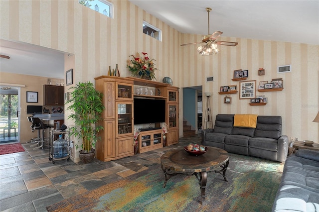 living room featuring ceiling fan and a towering ceiling