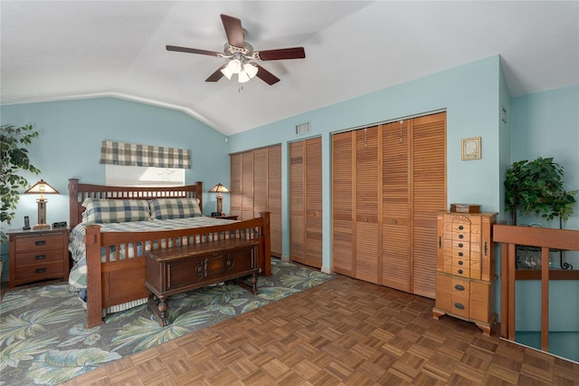 bedroom featuring lofted ceiling, dark parquet floors, ceiling fan, and multiple closets