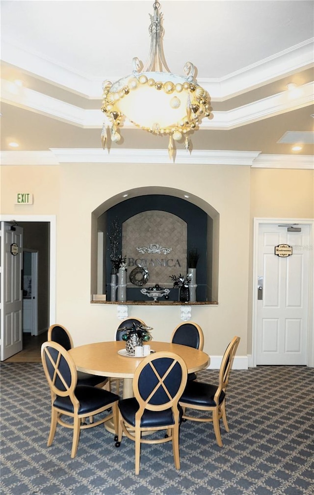 dining room featuring a raised ceiling, dark colored carpet, an inviting chandelier, and ornamental molding