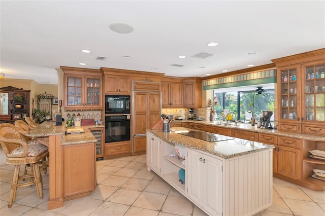 kitchen featuring a breakfast bar, black appliances, light stone countertops, light tile patterned floors, and kitchen peninsula