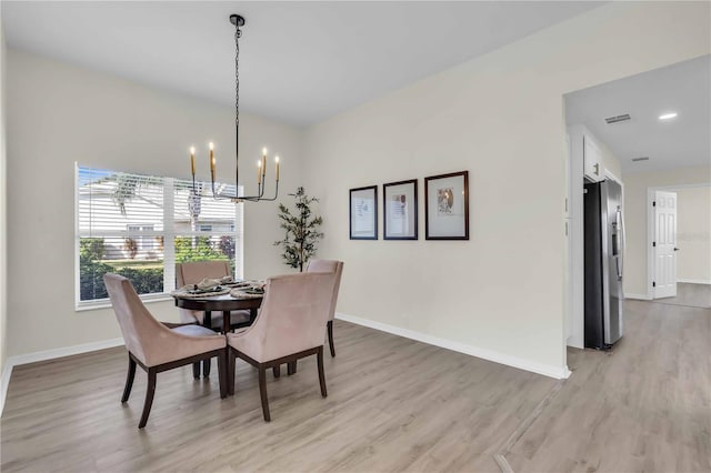 dining space with light wood-type flooring and a chandelier