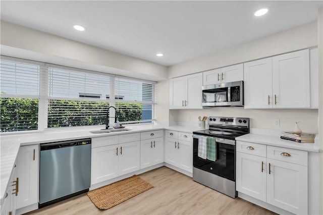 kitchen with appliances with stainless steel finishes, white cabinetry, and sink