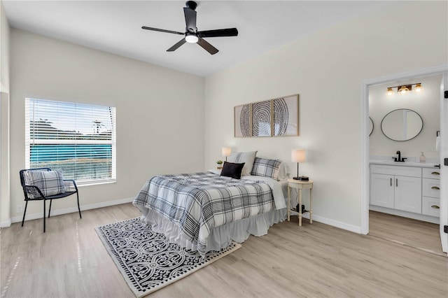 bedroom with ensuite bathroom, light hardwood / wood-style floors, sink, and ceiling fan