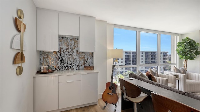 interior space with white cabinetry, decorative backsplash, floor to ceiling windows, and light hardwood / wood-style floors