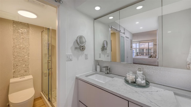 bathroom featuring wood-type flooring, toilet, a shower with door, and vanity