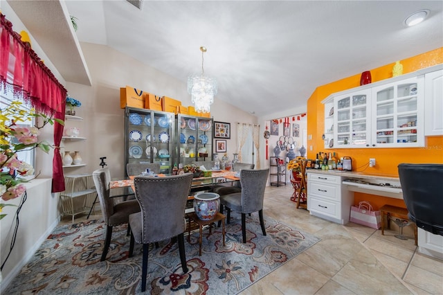 tiled dining area with a notable chandelier, built in desk, and lofted ceiling