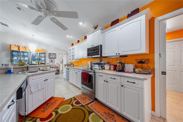 kitchen with pendant lighting, lofted ceiling, sink, appliances with stainless steel finishes, and white cabinetry